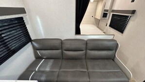 A modern interior with a grey sofa, a marble countertop, and a window with blinds. - New RV camper in great nature,spring valley (Hamden)