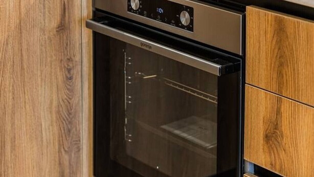 Una cocina con horno empotrado y cafetera sobre la encimera.