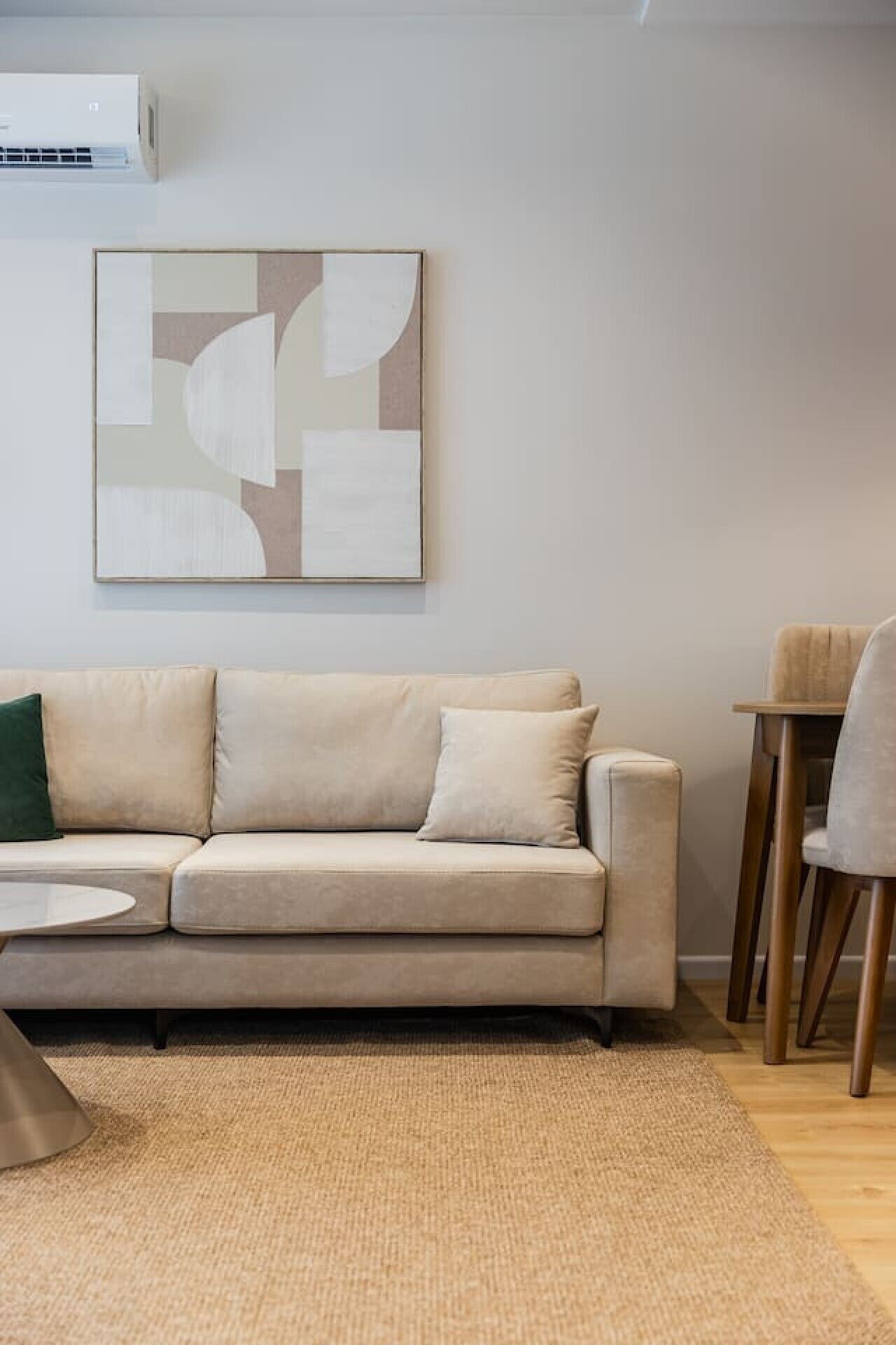 Una sala de estar con sofá color beige, una mesa de centro y un tapete.