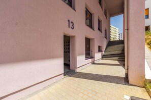 Un edificio con fachada rosa, una escalera que lleva a un nivel superior y el número 13 en la pared.