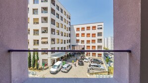 Un edificio de varios pisos con balcones y un estacionamiento en la parte delantera.