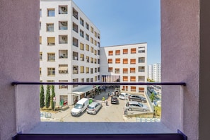 Un edificio de varios pisos con balcones y un estacionamiento en la parte delantera.