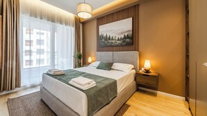 Een hotelkamer met een bed, nachtkastje, lamp en een schilderij aan de muur.