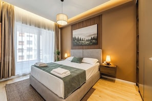Una habitación de hotel con cama, mesita de noche, lámpara y un cuadro en la pared.