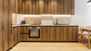 Een moderne keuken met houten kastjes, een inbouwoven en een aanrecht met spoelbak.