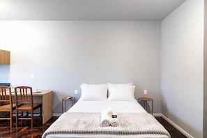 A hotel room with a bed, two bedside tables, a desk, and a chair. - Studio in Velha w/ City View Ola0002 (Blumenau)