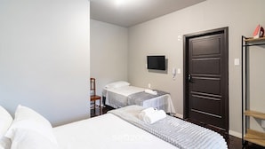 A hotel room with a bed, a chair, a desk, a TV, and a door. - Studio in Velha w/ City View Ola0002 (Blumenau)