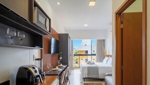 A compact hotel room with a kitchenette, a dining area, a bed, and a balcony with a city view. - Studio in Condo With Pool and Gym Azz0402 (Cabedelo)