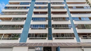 Un edificio de varios pisos con una banda vertical azul en el centro, grandes ventanales y techo plano.