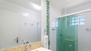 Un baño moderno con cabina de ducha de vidrio, un espejo grande y encimera de mármol.
