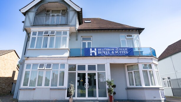 A two-story building with a sign for Heathrow Slough Hotel & Suites.