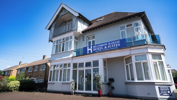Un edificio de dos pisos con un cartel que indica Heathrow Slough Hotel & Suites.