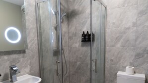 A modern bathroom with a glass-enclosed shower, a white sink, and a toilet.
