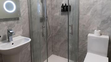 Kylpyhuone, jossa on lasiseinällä varustettu suihku, pesuallas ja wc.