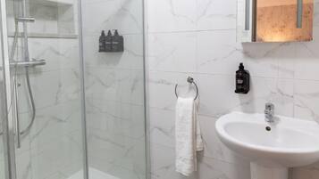 A bathroom with a glass shower enclosure, a white sink, and a mirror.