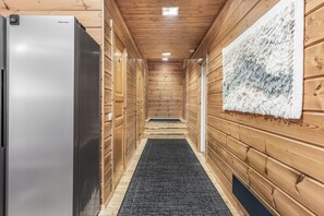 Ein Flur mit Holzwänden, einem schwarzen Teppich und einer weißen, strukturierten Wanddekoration.