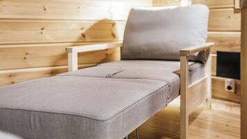 Una cama individual con colchón y almohada grises en una habitación de madera con una lámpara de noche.