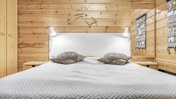 Una habitación con piso de madera, una cama, dos mesitas de noche y un tapiz decorativo en la pared.