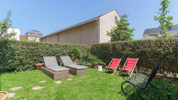 A backyard with two wicker lounge chairs, a red chair, and a metal bench. - Apartment in the Heart of Deauville With a Garden (Deauville)