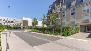 A residential street with modern apartment buildings, a clear sky, and a pedestrian pathway. - Apartment in the Heart of Deauville With a Garden (Deauville)