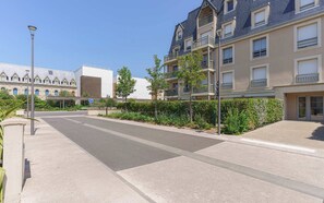A residential street with modern apartment buildings, a clear sky, and a pedestrian pathway. - Apartment in the Heart of Deauville With a Garden (Deauville)