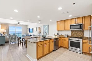 Una cocina moderna con encimeras de granito, electrodomésticos de acero inoxidable y armarios de madera.