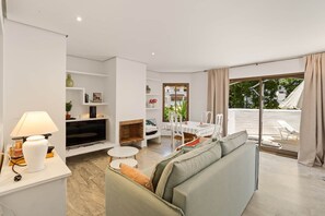 Ein modernes Wohnzimmer mit einer Couch, einem Fernseher und einem Essbereich mit Tisch und Stühlen.