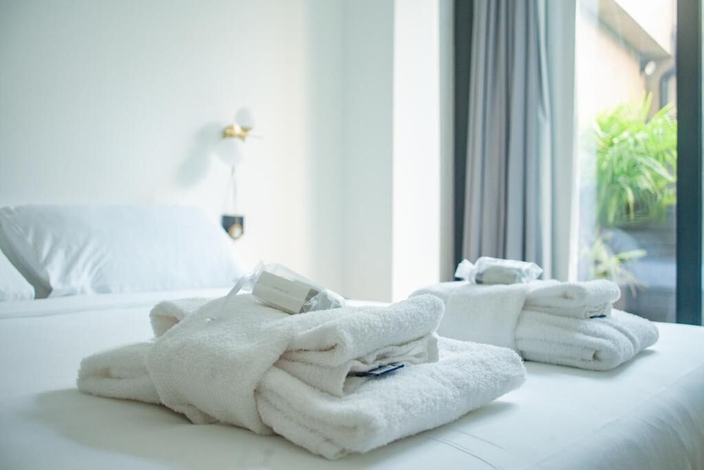 A neatly made bed with folded white towels and a bedside table with a lamp.