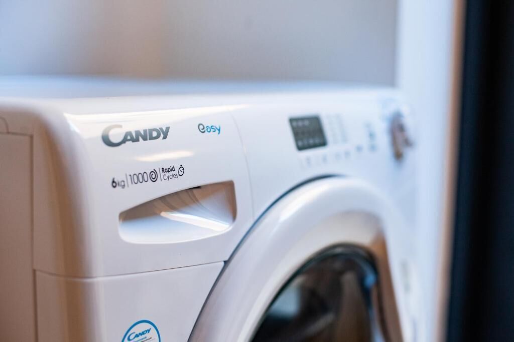 A white Candy Easy front-loading washing machine with a control panel and a door.