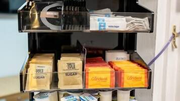 Un présentoir à plusieurs niveaux, où sont exposés divers produits emballés, notamment des boîtes de sucre, des condiments et des produits laitiers.
