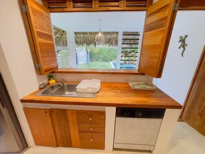 A compact kitchen with a built-in dishwasher, a sink, and wooden cabinetry. - Serene Eco Villa 3BR and private pool (Las Terrenas)