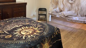 Ein Schlafzimmer mit Bett, Deckenventilator, Sessel, Kommode und einer großen Wandmalerei.