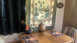 Ein Holztisch mit zwei Untersetzern, einer Blumenvase und einer Wanddekoration mit einem Willkommensschild.
