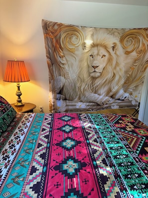 Une pièce décorée d’une grande tapisserie représentant un lion, d’un couvre-lit à motifs et d’une lampe de table.