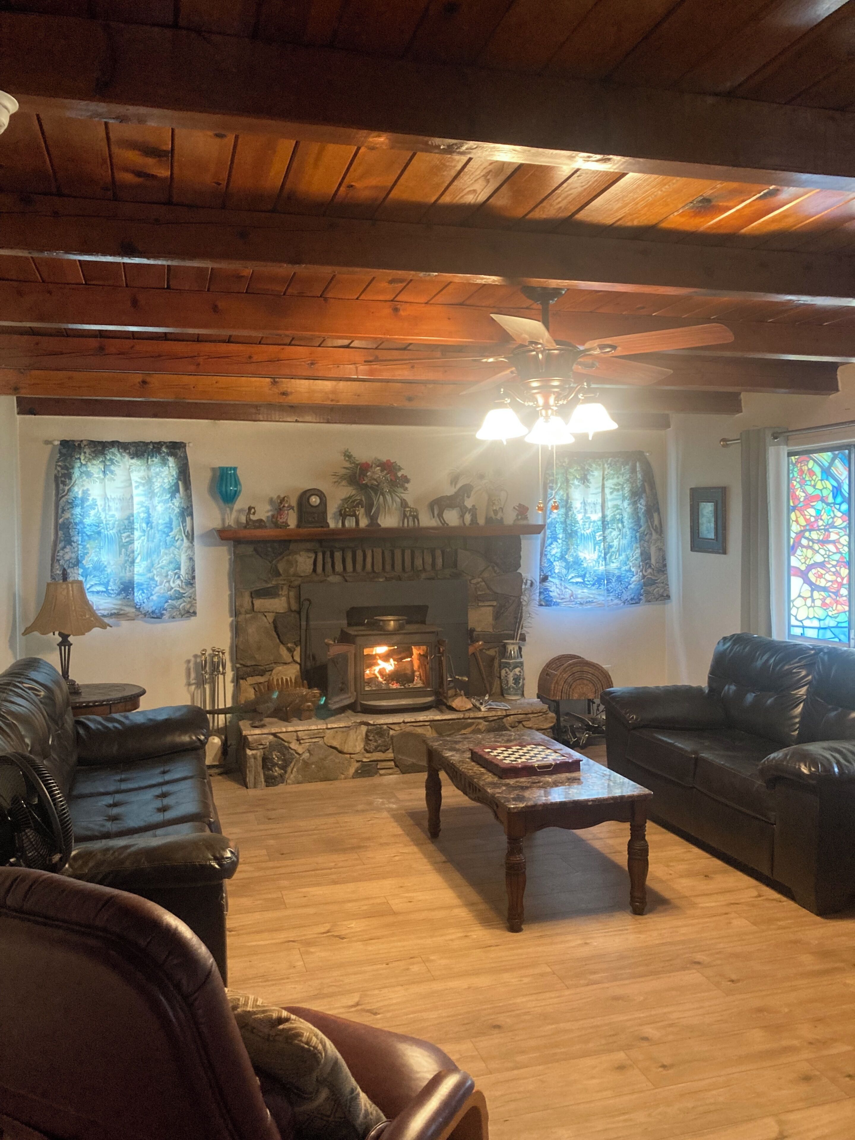 A cozy living room with a fireplace, leather sofas, and a wooden ceiling.
