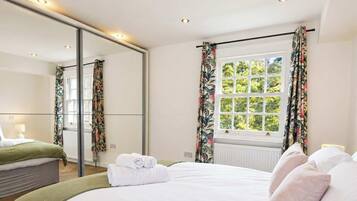 Une chambre d’hôtel avec un lit, un grand miroir, une fenêtre avec des rideaux et un radiateur.