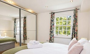 Habitación de hotel con cama, un espejo grande, una ventana con cortinas y un radiador.