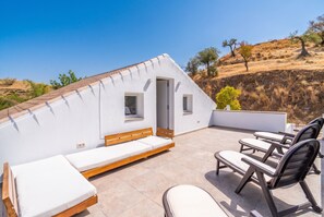 A rooftop terrace with a white exterior, a wooden bench, and several lounge chairs. - Cubo's Violeta Rural House Family / Private pool / BBQ / Air conditioning / Free Wi-Fi (Coín)