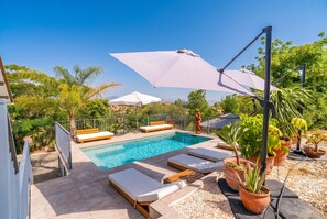 A swimming pool with sun loungers and umbrellas, surrounded by greenery and a clear sky. - Cubo's Violeta Rural House Family / Private pool / BBQ / Air conditioning / Free Wi-Fi (Coín)