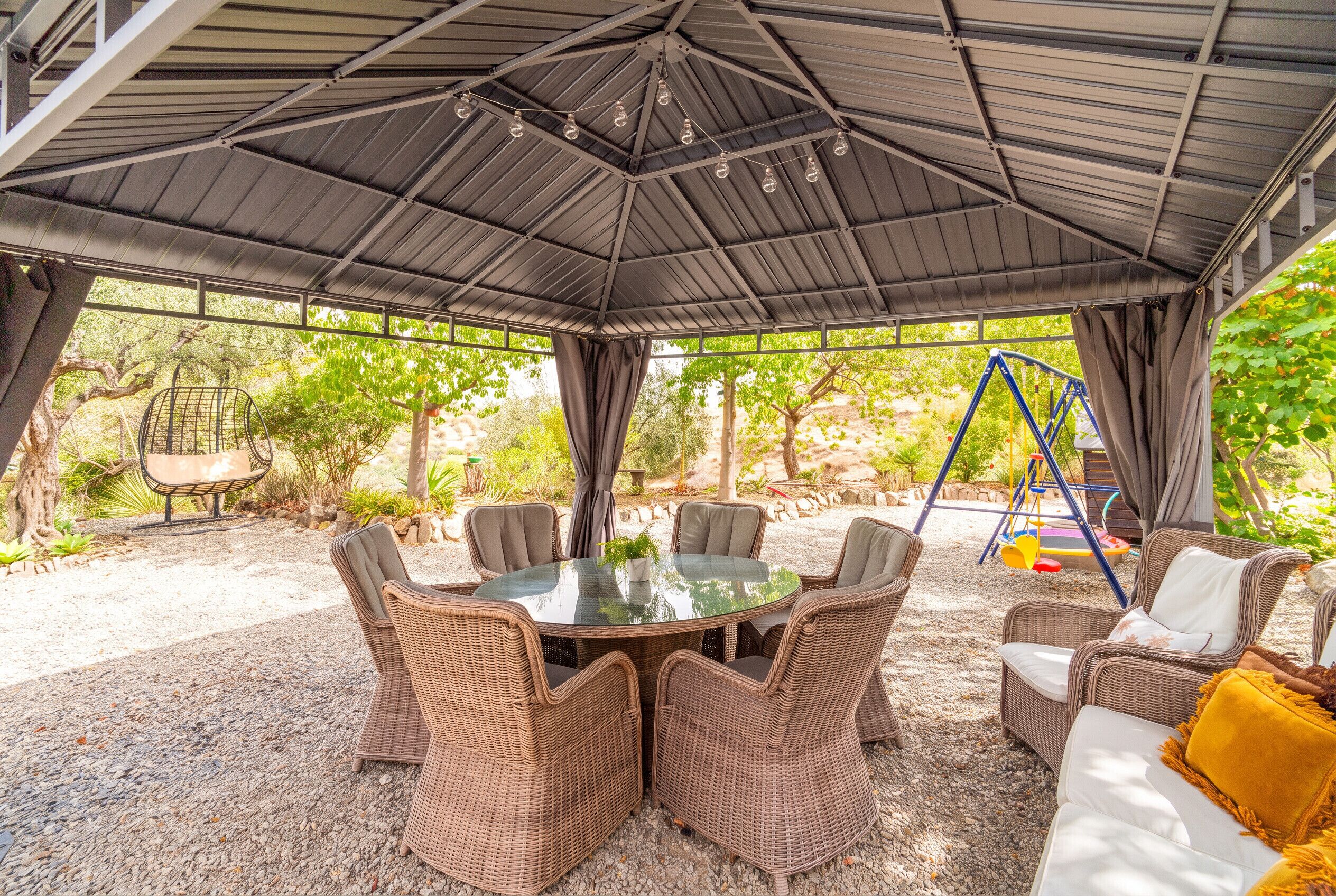 A covered outdoor seating area with wicker furniture and a glass table.