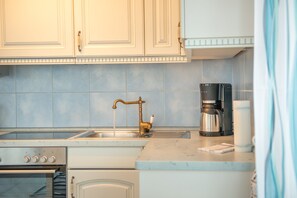 A kitchen with a double sink, a coffee maker, and a stove.