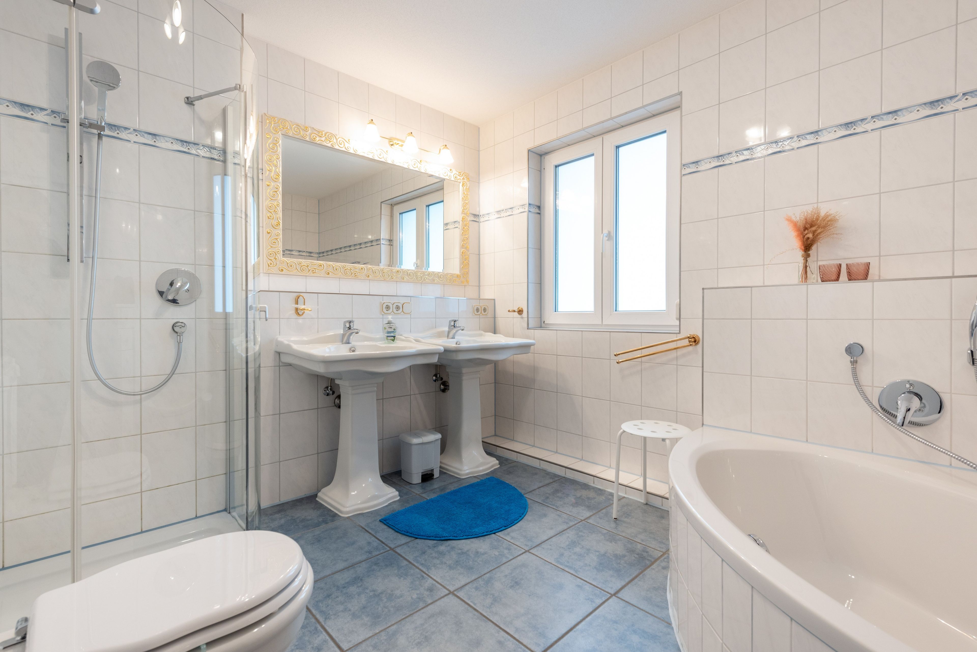 Ein modernes Badezimmer mit Dusche, zwei Waschbecken, Toilette und Badewanne.