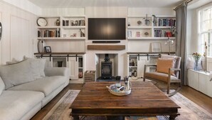 Una sala de estar con sofá, mesa de centro, chimenea, televisor y estanterías.