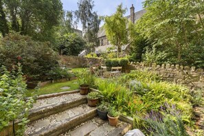A garden with stone steps leading to a seating area, surrounded by various plants and a stone wall. - Central Edinburgh Retreat with Sunny Garden (Edinburgh)