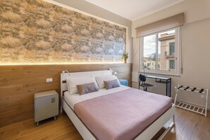 A bedroom with a bed, bedside tables, a window with a view, and a decorative wall. - La Carezza dei Vicoli "Oro e Malva" Apartment in the Historic Center (Palermo)
