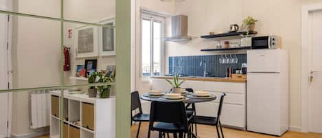 A modern kitchen with white appliances, a dining table with chairs, and a hanging light fixture.