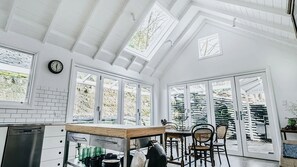 Una cocina luminosa con paredes blancas, encimera de madera y un comedor con sillas.