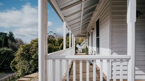 Eine weiße Holzbalkon mit einer Holztreppe, die zu einer Tür führt.