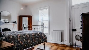 Ein Schlafzimmer mit einem Bett, einem Schminktisch, einem Spiegel, einer Heizung und einem Fenster.