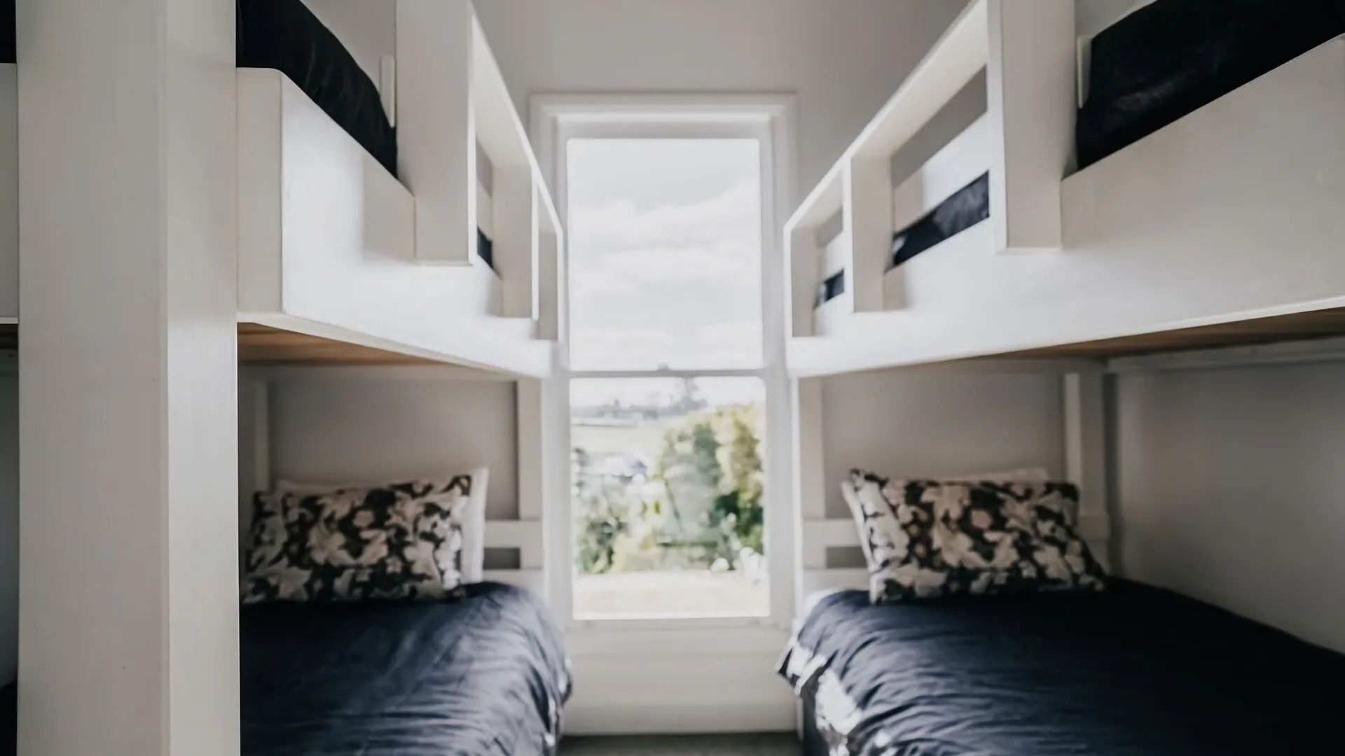 A dormitory room with two beds, each with a pillow and a headboard.